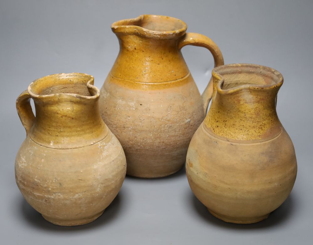 A group of three late 19th century part glazed Verwood pottery pitchers, tallest 25cm